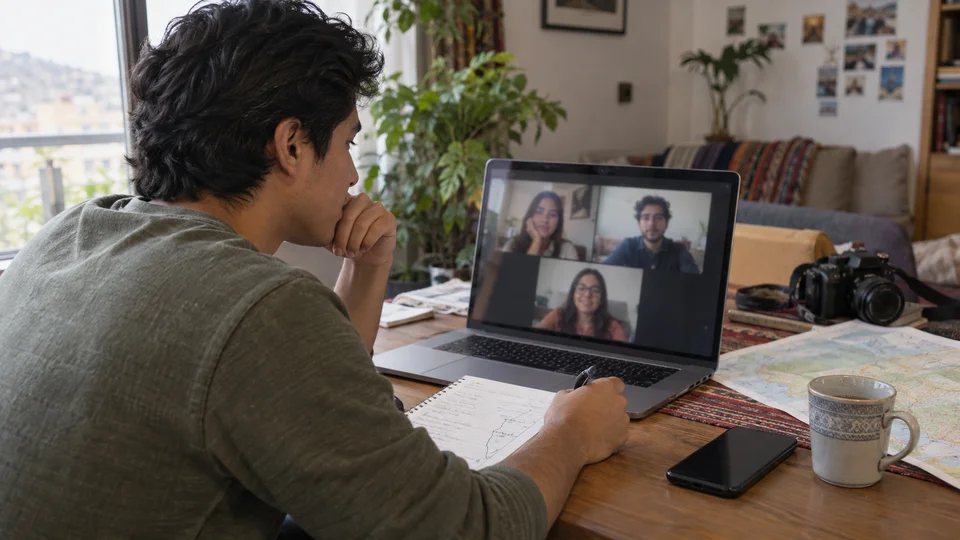Digital nomad on a video call with family members, laptop on a home office desk.
