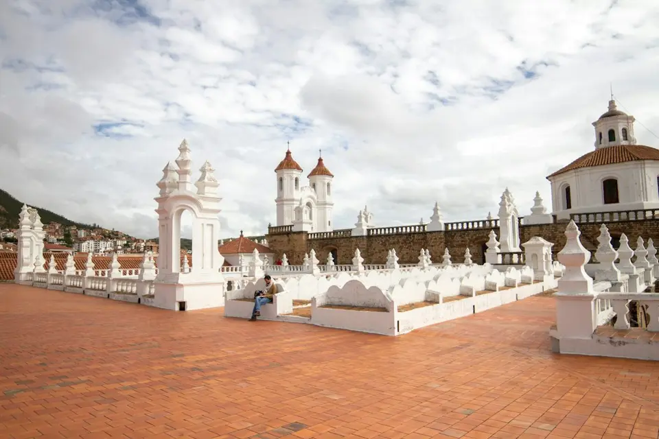 White colonial church with domes in the Andean highlands of Bolivia, showing religious architecture.