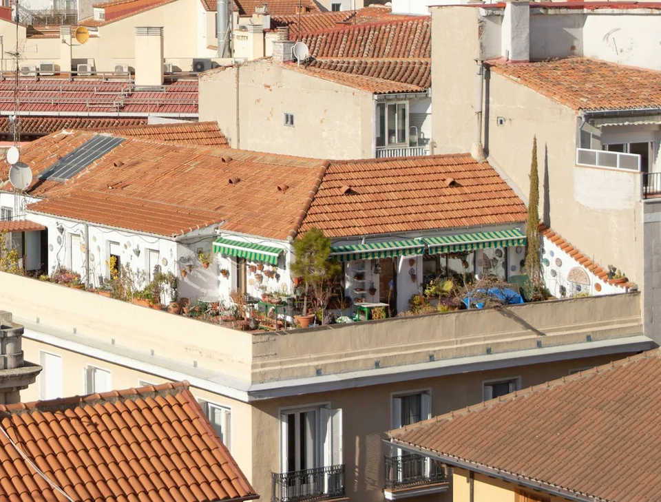 Sunlit rooftops of a Spanish city with traditional terracotta tiles and white buildings.