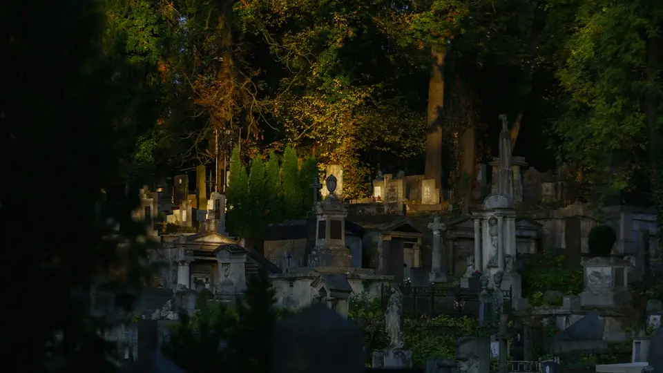 Nighttime cemetery with illuminated stone graves and trees, evoking the traditions of Haitian Fèt Gede.