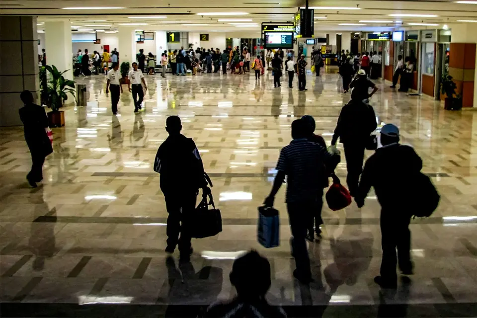 Passagers avec bagages dans un terminal aéroportuaire avec tableaux d'affichage au-dessus