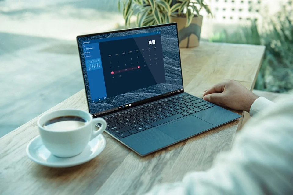 Laptop and coffee cup on a table overlooking the sea, digital nomad workspace.