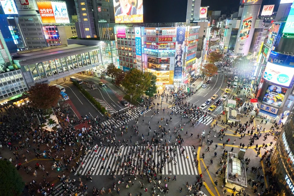 Aerial view of the Shibuya crossing in Tokyo at night with neon signs and crowds