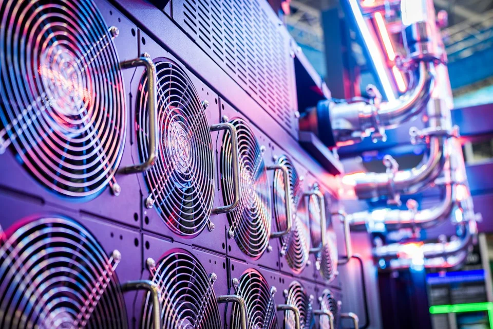 Server cooling fans in a data center room lit in blue and pink.