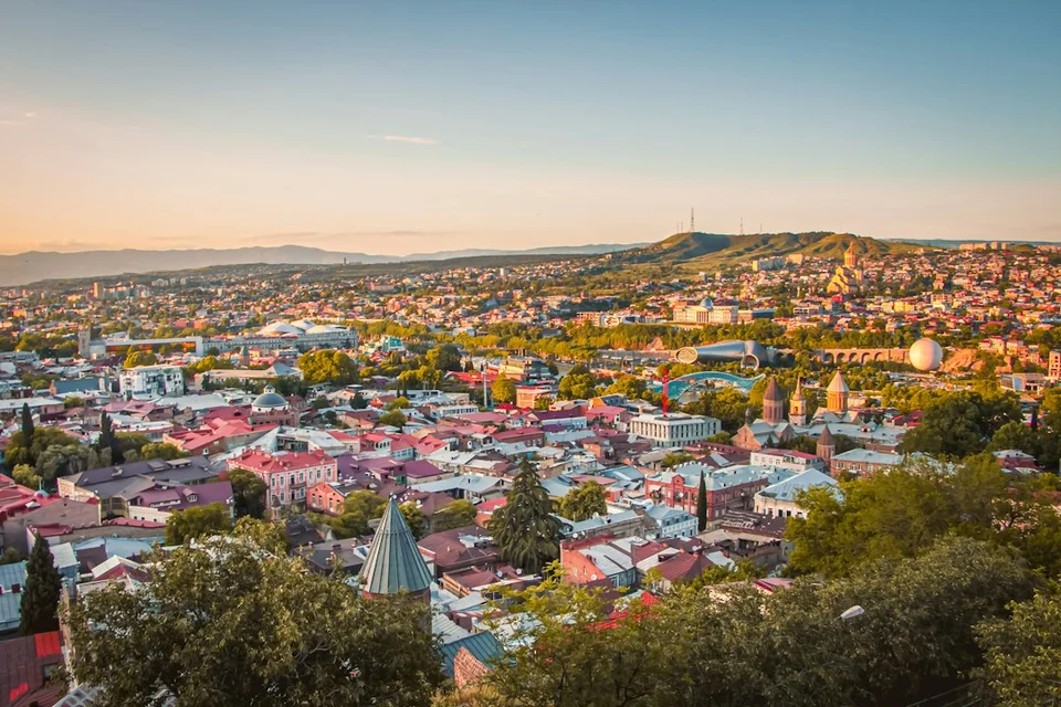 Luchtfoto bij zonsondergang van de oude stad van Tbilisi met kleurrijke daken, kerkkoepels en omliggende wijken.
