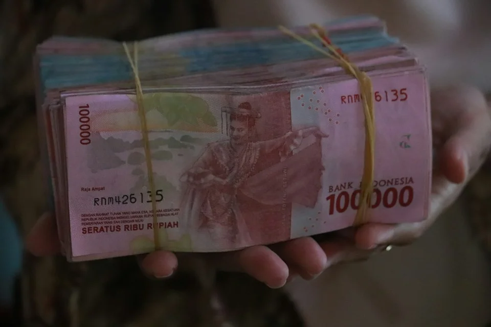 Bundel Indonesische roepiabiljetten in de hand, met zichtbaar de coupure en de merktekens van de Bank van Indonesië.